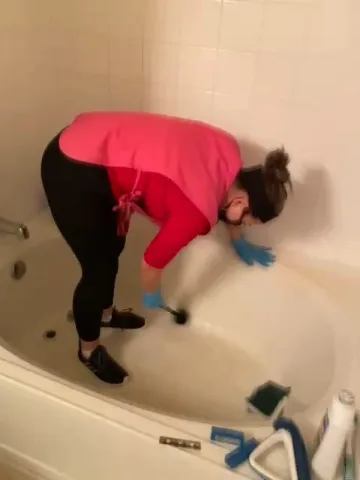 Cleaner scrubbing a bathtub by hand