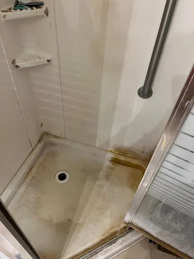 Shower pan before cleaning with buildup stains